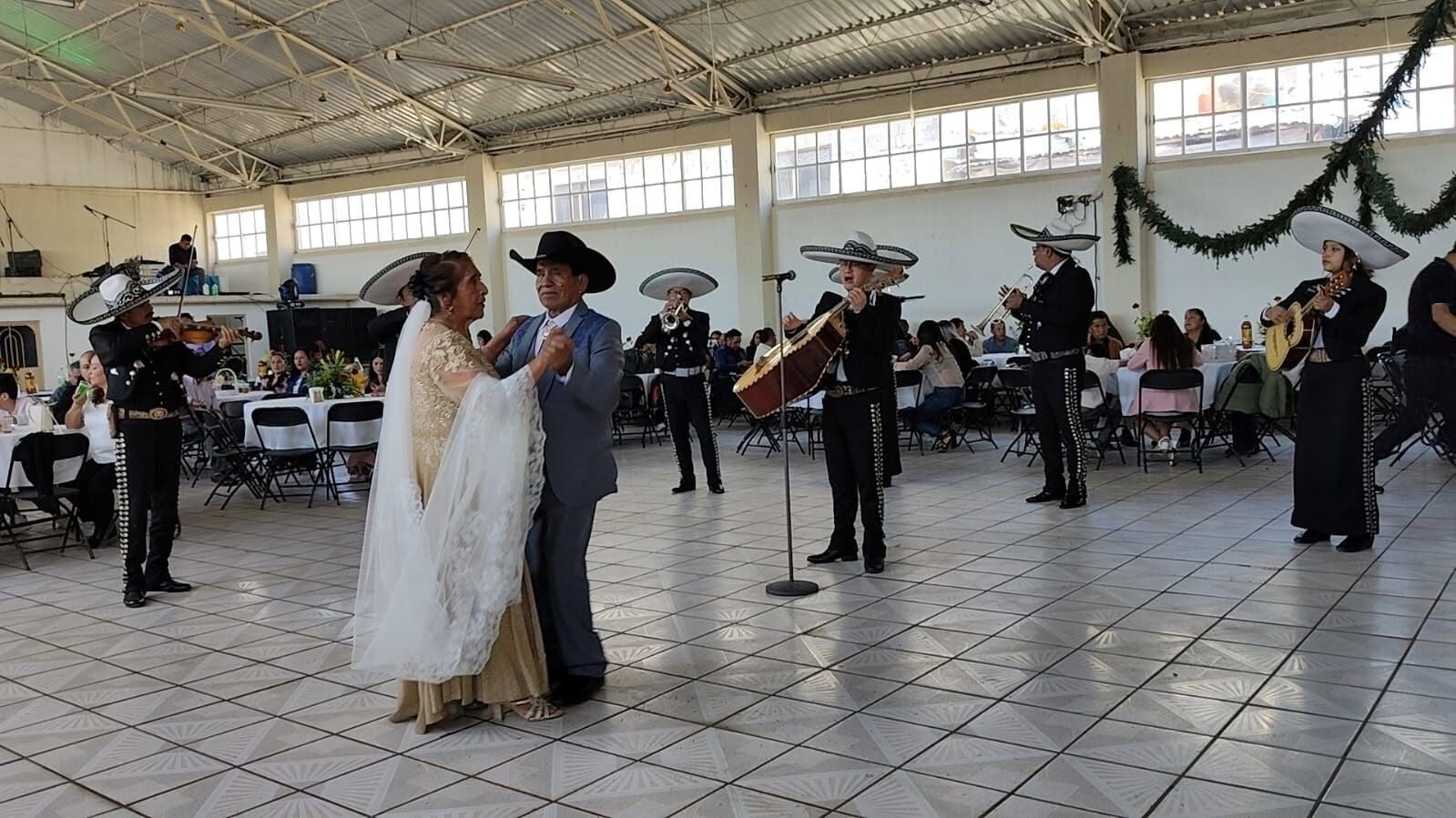 Pareja bailando con mariachi en salón de fiestas
