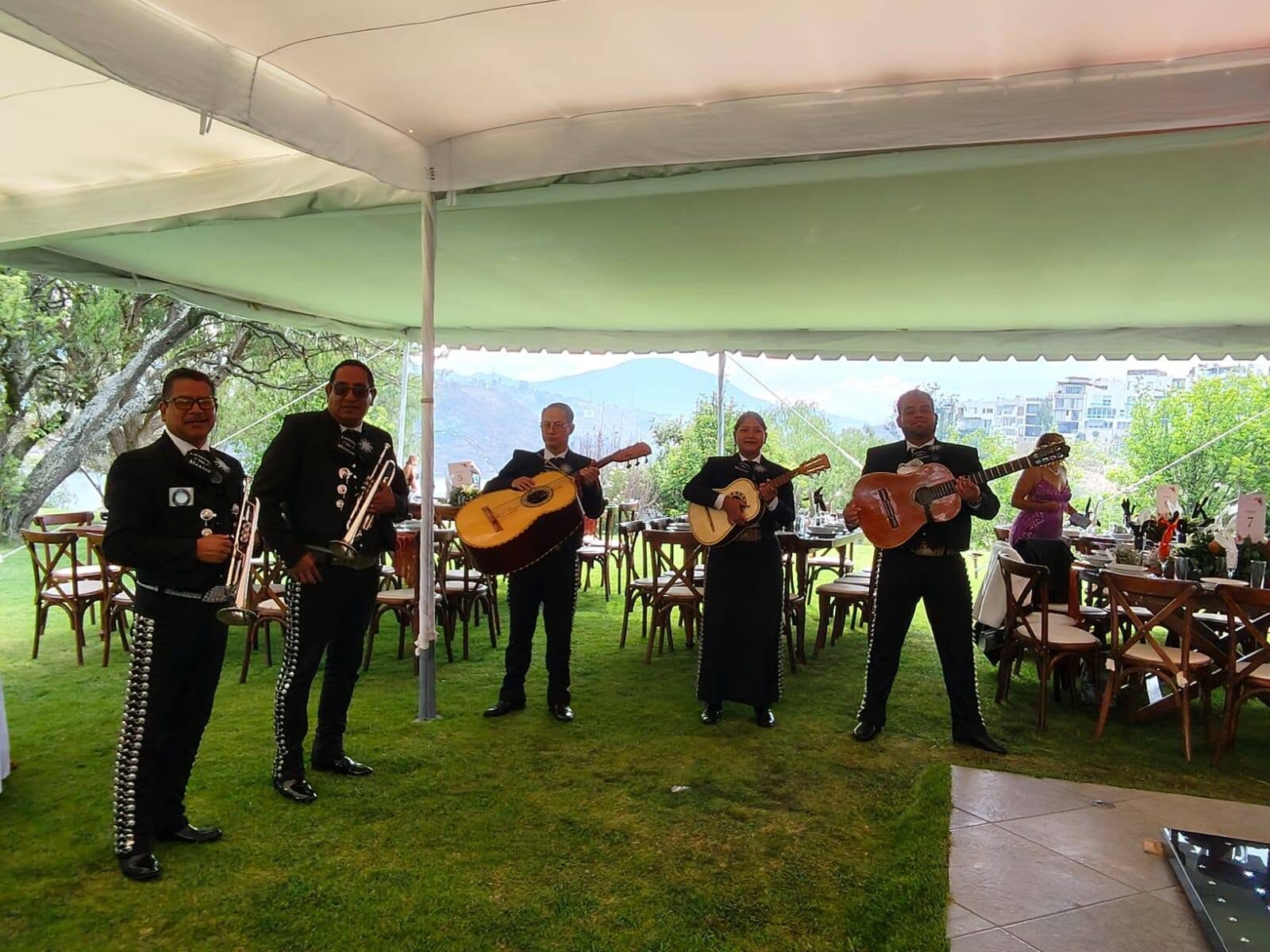 Mariachi tocando bajo carpa en jardín con vista panorámica